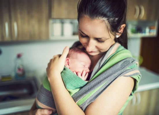 אם נושאת תינוק באמצעות מנשא בד